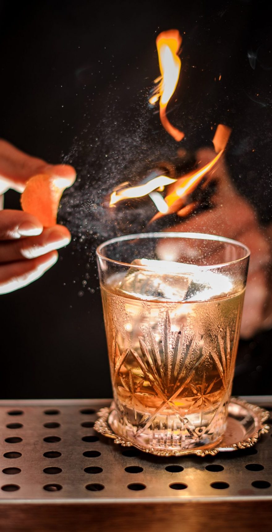 Barman making a fresh and tasty old fashioned cocktail with orange peel and smoke note Barman making a fresh and tasty old fashioned cocktail with orange peel and smoke note on the bar counter